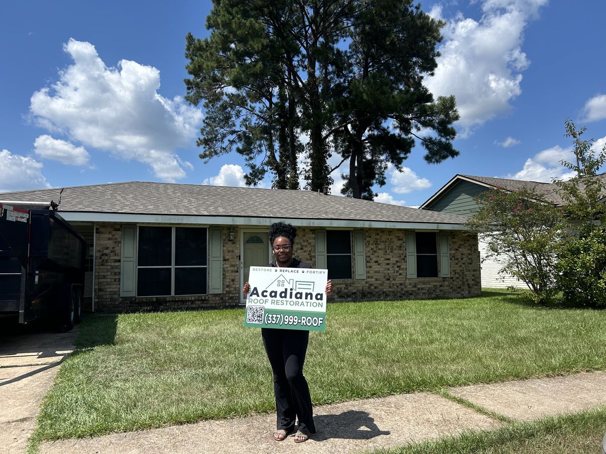 Happy Acadiana homeowner with Acadiana Roof Restoration yard sign